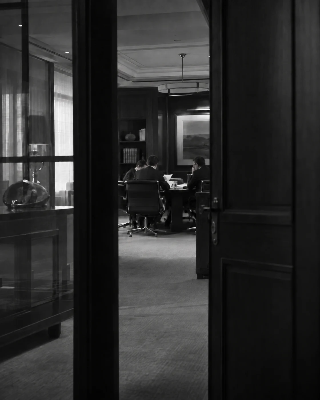 A distant team reviewing documents, glimpsed candidly through a glass office partition